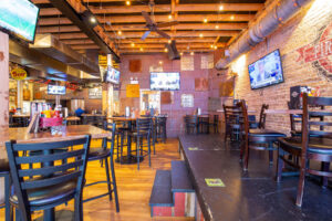 Warm restaurant interior with exposed brick and TV screens